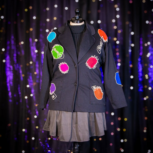 Black blazer with colorful patches on a mannequin against a sparkling curtain background